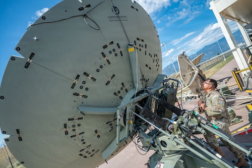 U.S. Space Force Guardian working beside a large ground communications antenna